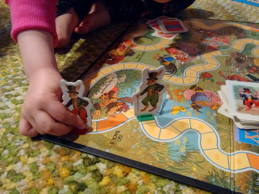 a small child's hand moves a game piece on a game board