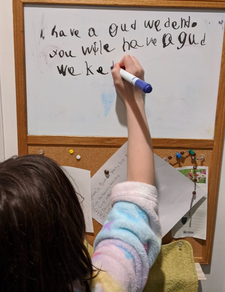 Child writing phonetically on a white board about having a good idea...
