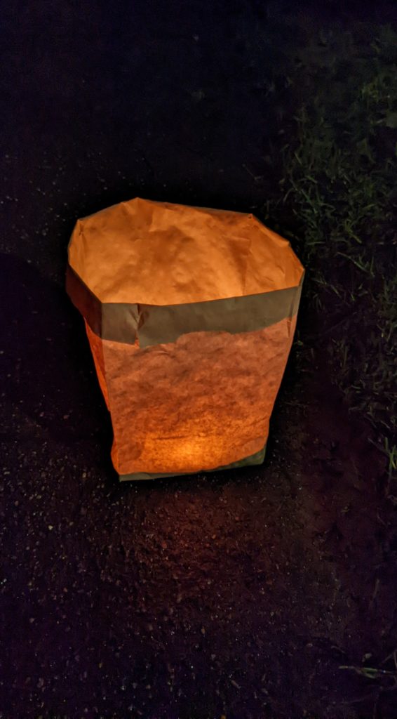 Picture of a paper bag luminaria glowing in the dark